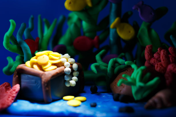 橡皮泥水下景观。海洋和海底世界的背景，珊瑚和打开海盗的箱子闪闪发光的金子。图片下载