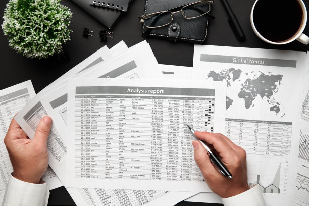 俯视图的商人的手工作与财务报告。现代黑色的办公桌上有笔记本，铅笔和很多东西。平铺表布局。图片下载