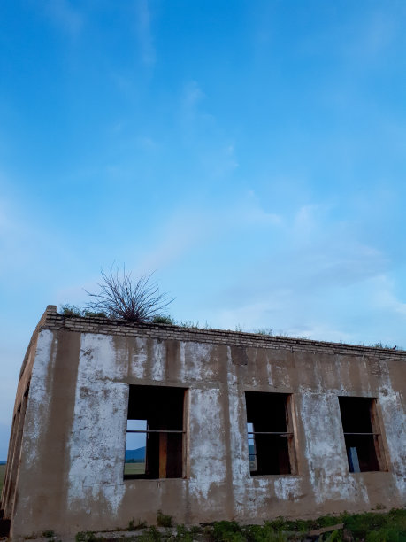 这张照片拍摄的是一个没有窗户的废弃建筑，在夏天黄昏的光线下，有粉红色的天空和云彩图片下载