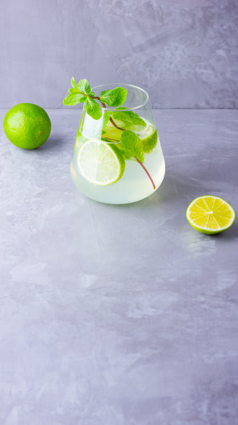 莫吉托鸡尾酒，柠檬和薄荷杯。灰色背景上的玻璃莫吉托。清新的薄荷鸡尾酒加酸橙。注入水。本空间图片下载