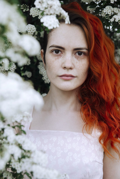 1个白色漂亮时髦的女人，红头发，穿着粉红色的裙子，在绿色和白色的鲜花中，一个女孩和一个盛开的花园图片下载