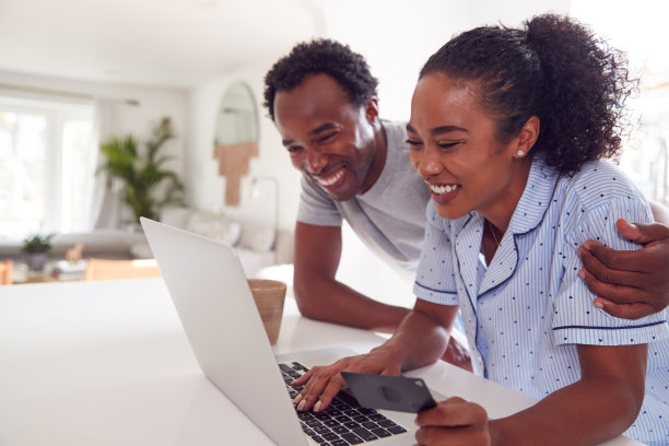 在厨房里穿着睡衣的夫妇正在用笔记本电脑在线购买信用卡图片下载