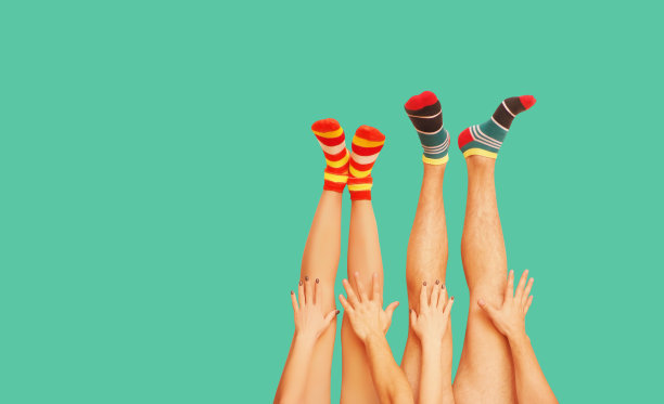 有趣的条纹袜子。已婚夫妇的腿。被隔离在草地上。图片下载