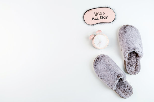 平躺着柔软的毛绒拖鞋灰色和粉红色的闹钟孤立在白色的背景。顶视图，开销，模型，模板，复制空间。时间休息图片下载