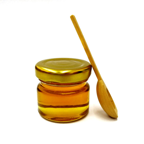 白色木质背景上有一个木勺的蜂蜜玻璃瓶。图片下载