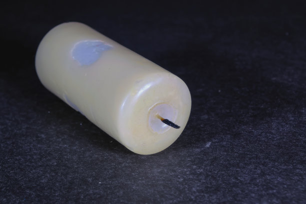 在黑暗的特写背景上，一支褪色的蜡烛。图片下载