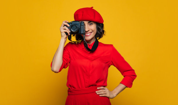 大家都笑得很开心!一个可爱的露齿微笑的女人在她的假期的半长照片，法国风格的穿着，带着一个相机在她的脖子上，准备拍照。图片下载