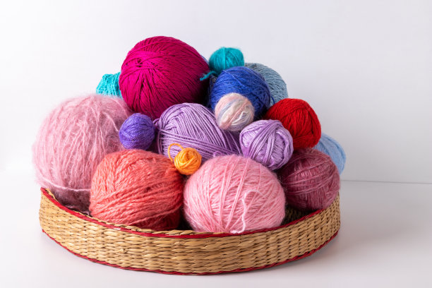 编织用的多种颜色的线球，放在一个柳条架上，放在一个明亮的背景上。图片下载