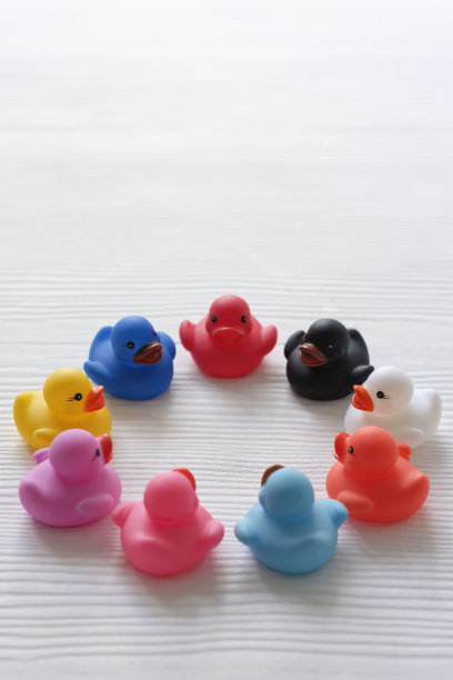群圈的多色橡皮鸭，围坐成一圈仿佛在圆桌会议/讨论/峰会，场景设置在白色木纹纹理的背景上。图片下载