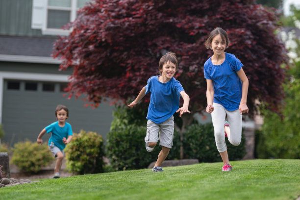 三个孩子在外面跑过一片草地图片下载