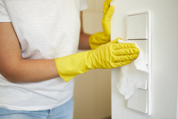 一名妇女戴着橡胶手套用消毒湿巾消毒和清洁电灯开关的各种照片图片下载