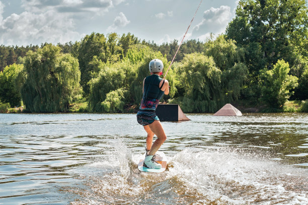 女人骑花式滑水。在夏日的湖中切浪溅起水花图片下载