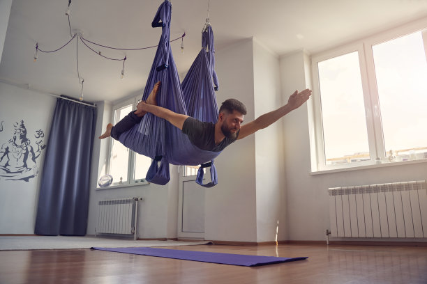 蓄着胡须的运动员在做反重力瑜伽运动图片下载