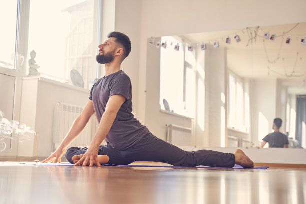 英俊的年轻人做坐鸽子瑜伽姿势图片下载