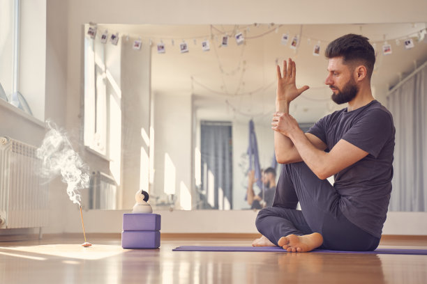 男性瑜伽练习者在工作室做半鱼主的姿势图片下载