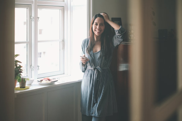 微笑的亚洲年轻女子用手机，在拍了一张在家吃早餐的照片后分享到社交媒体上。图片下载