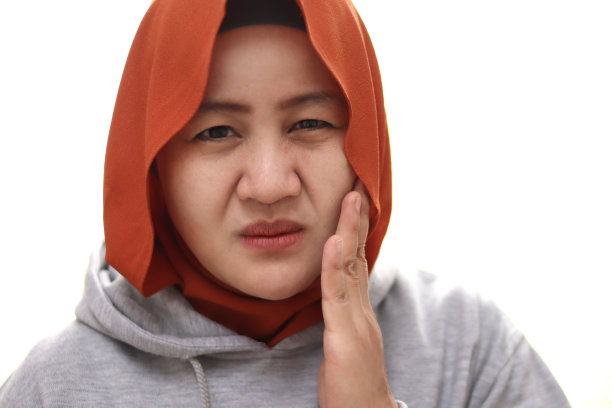一位年轻漂亮的亚洲穆斯林妇女因牙痛而感到痛苦，与白色背景隔离图片下载