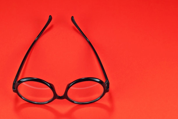 不同类型的眼镜在一个红色的背景上接近。圆框眼镜。布局设计。文本空间和对象附近的自由空间。图片下载