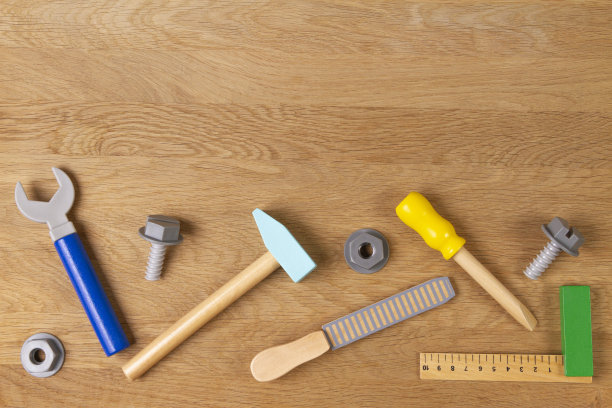 木制儿童玩具螺丝刀，钳子，螺栓，螺母等施工工具框架上的木材背景。俯视图，平放图片下载