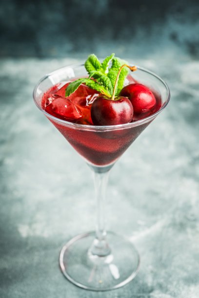樱桃鸡尾酒在马提尼杯与浆果和薄荷叶图片下载