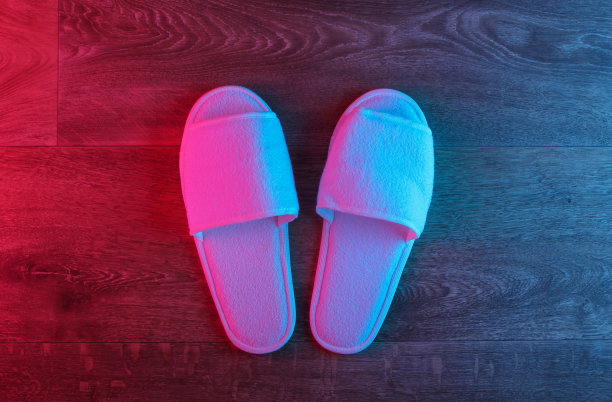 白色拖鞋在木地板上，霓虹红蓝渐变辉光。俯视图图片下载