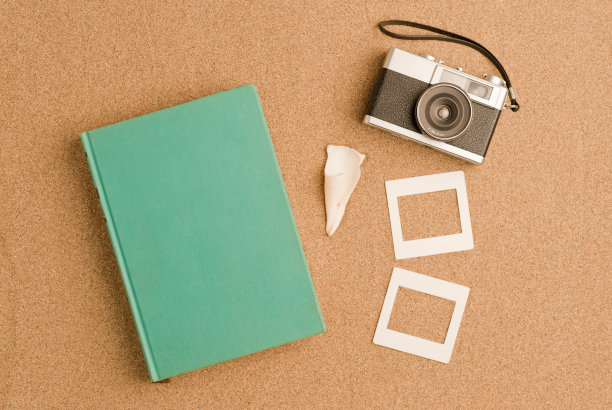 度假、旅游和暑假概念:淡蓝色的书，配有复古的照片相机，被贝壳放在沙滩上的沙滩上设置方形相框。摄影设计说明图片下载