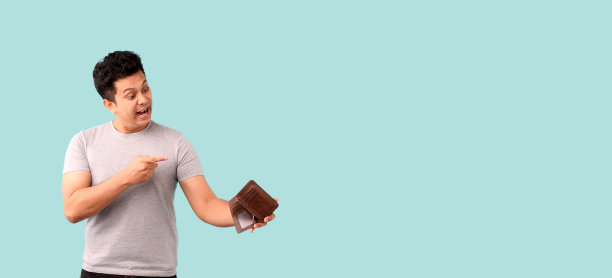 英俊的亚洲男人，一个快乐的微笑，在工作室的蓝色背景上拿着一个空钱包，复印空间。图片下载