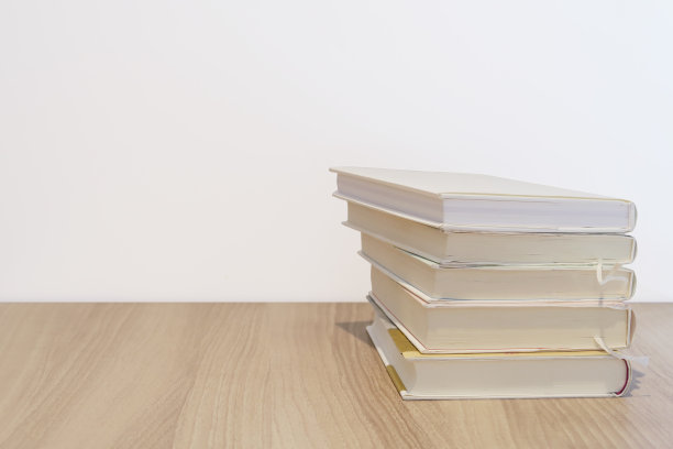 成堆的书放在木桌和白色的墙壁上图片下载