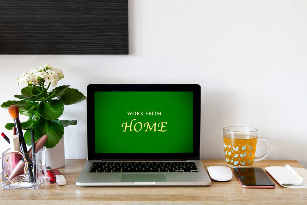 在家工作，桌上放着笔记本电脑。在照片的墙上。一个杯子。手机,笔记本。图片下载