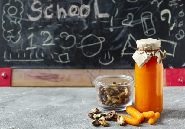 健康儿童超级食物概念。Сarrot果汁和坚果在学校黑板的背景。图片下载