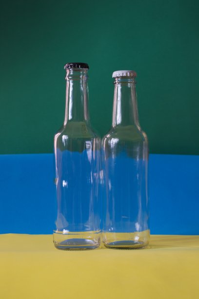 肖像图像的两个空透明玻璃瓶的背景黄，蓝和绿色。图片下载