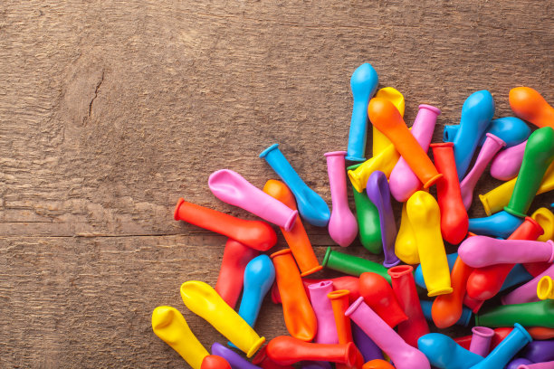 一堆没有充气的气球，不同颜色的木头背景。图片下载