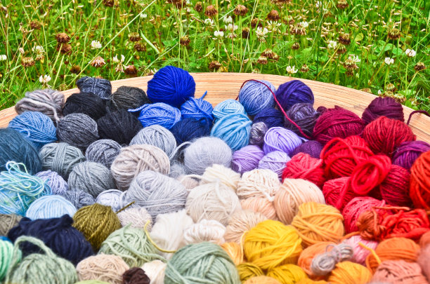 许多彩色的和充满活力的球，毛线，躺在一个大木碗站在绿色草地上的特写图片图片下载