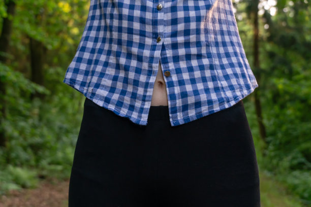 一个年轻苗条的女人在锻炼后的肚脐可以透过衬衫看到图片下载