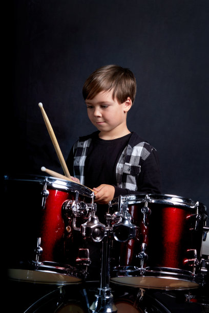 垂直照片的一个孩子与乐器，鼓。深蓝色的背景图片下载