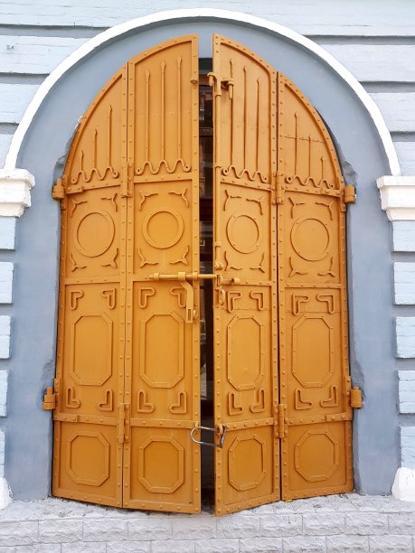 中世纪的金属锻铁门，镂空的沉重锻铁大门在蓝色墙壁的衬托下呈黄色。图片下载