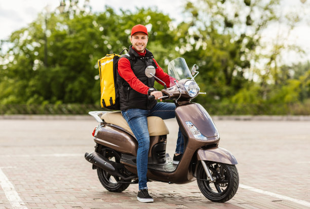 骑着踏板车在户外送餐厅食物的快递员图片下载