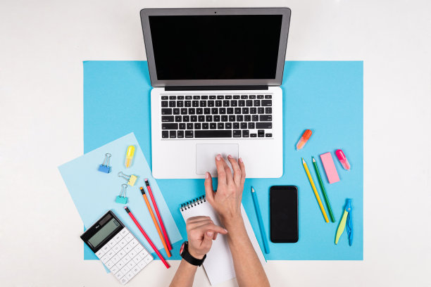 手机在手，笔记本电脑，文具孤立在白色和蓝色的背景图片下载