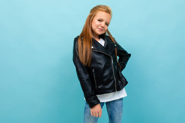 白人少女在黑色夹克和牛仔裤微笑孤立在蓝色背景图片下载