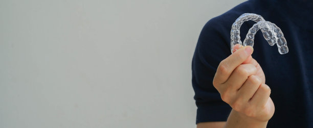 近距离的年轻亚洲男子手握牙科矫正器固位器(看不见)在牙科诊所为美丽的牙齿治疗课程的概念图片下载