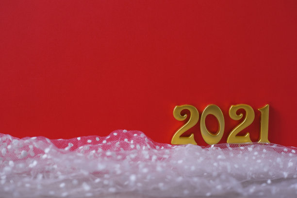 新2021年。红色背景的人造雪上刻着金色数字2021。节日的照片图片下载