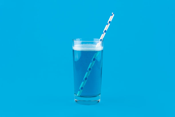 蓝色的柠檬水，气泡和鸡尾酒吸管孤立在蓝色背景图片下载