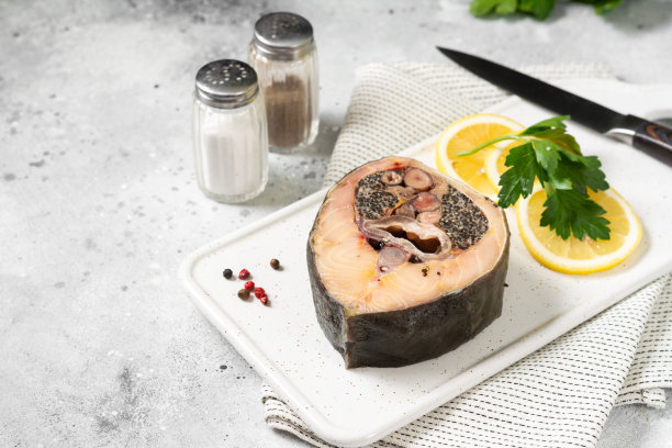 浅灰色的餐桌上，白色陶瓷盘子上放着野生鲟鱼排。健康的海鲜。带有文本空间图片下载