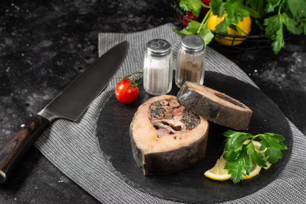 黑餐桌上的一块黑石板上放着野生鲟鱼牛排。健康的海鲜图片下载