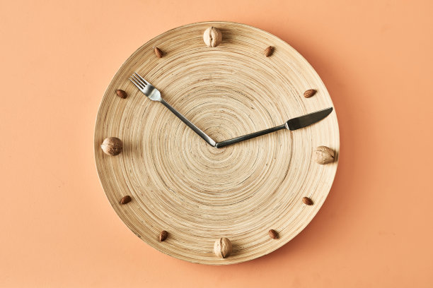 厨房时钟由坚果，叉子和刀孤立在米色背景，概念摄影健康食品博客图片下载