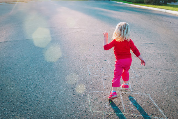 日落时分，小女孩在外面玩跳房子图片下载