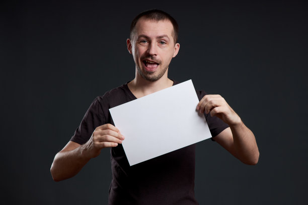男子手里拿着一张空海报纸。微笑和欢乐，文字的地方，复制的空间图片下载