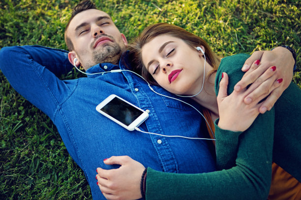 一对年轻夫妇正在公园里听音乐图片下载