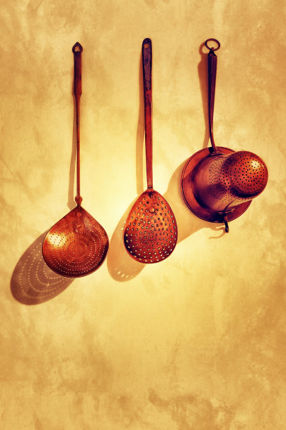 墙上挂着一个古铜色的滤锅。三种不同的类型。图片下载