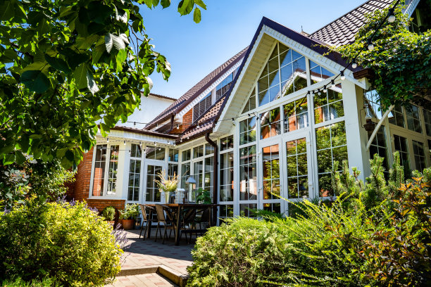 白色的夏日别墅，有全景的窗户。小屋花园中的庭院和餐桌。图片下载